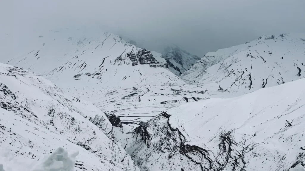 Wide snowy mountain valley beneath an overcast sky.